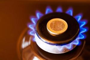 quemador de estufa de gas con una moneda de euro encima, quemando gas natural con llama azul foto