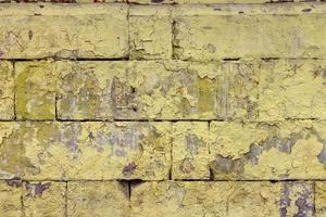 peeled off old yellow paint on flat rough brick wall surface - full frame background and texture photo