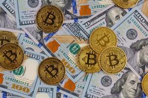 yellow bitcoin coins scattered over US dollar paper banknotes photo