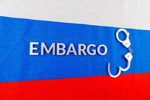 word embargo laid with silver letters on russian flag with silver handcuffs photo