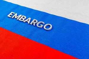 word embargo laid with metal letters on russian tricolor flag in diagonal view photo