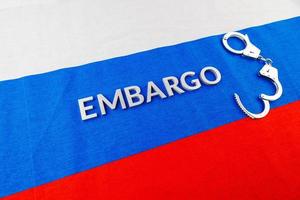 word embargo laid with silver letters on russian flag with silver handcuffs photo