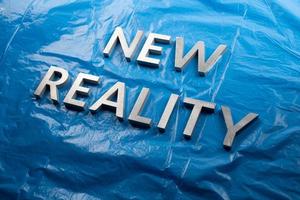 the words new reality laid with white letters over crumpled blue plastic film background - slanted perspective photo