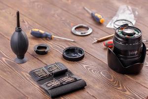 lente de zoom de cámara medio desmontada sobre una mesa de madera rodeada de herramientas foto