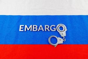 word embargo laid with silver letters on russian flag with silver handcuffs photo