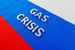 the words gas crisis laid with silver letters over flat russian flag surface photo