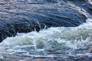 agua que fluye de un río de verano con una pequeña cascada rápida a la luz del atardecer foto