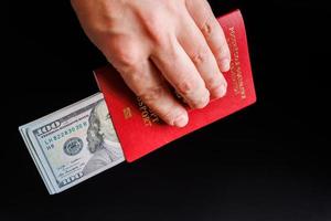 caucasian hand holding russian international passport with inserted US dollars photo