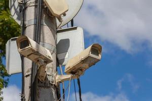 two old cctv security surveillance cameras on street light pole on blue sky background photo