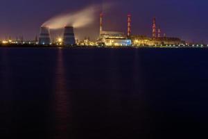 old thermal 450 megawatt power plant at night with artificial lake on foreground photo