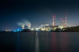 old thermal 450 megawatt power plant at night with artificial lake on foreground photo