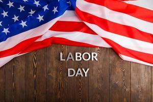 words labor day laid with silver metal letters on wooden surface with crumpled USA flag on upper side photo