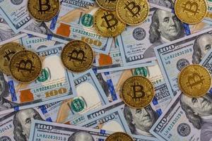 yellow bitcoin coins scattered over US dollar paper banknotes photo