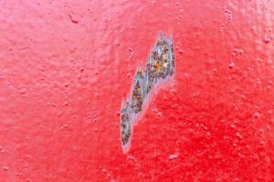 red painted metal surface with local rusted scratch - close-up with selective focus photo