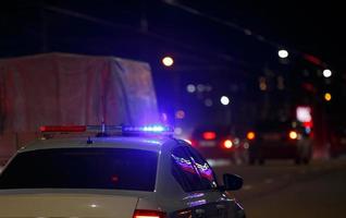 coche de policía de carretera irreconocible con luz de sirena roja y azul encendida en su techo en la carretera nocturna de la ciudad foto