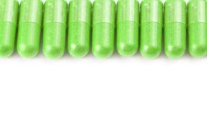 row of ufo green color organic capsules isolated on white background closeup with selective focus photo