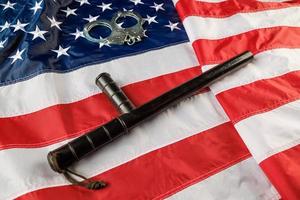 silver metal handcuffs and police nightstick over US flag on flat surface photo