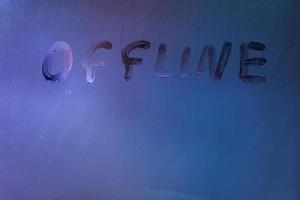 word offline handwrittern en vidrio empañado con luz de fondo azul neón frío foto