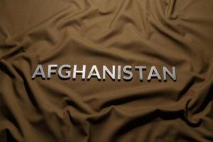 the word afghanistan laid with silver metal letters on crumpled tan khaki canvas fabric photo