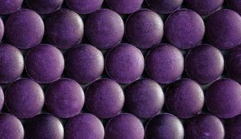 un patrón hexagonal sin costuras de muchas tabletas de espirulina orgánica púrpura colocadas apretadas en una capa sobre una superficie plana foto