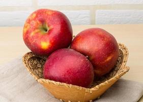 Red apples in a basket on wooden background photo