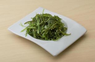 Chuka salad on the plate and wooden background photo