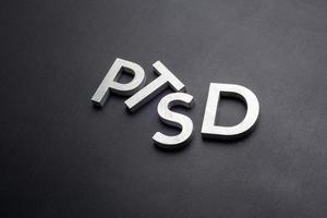 the word PTSD laid with silver metal letters on flat black background photo