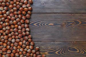 hazelnuts with shells laid on brown wooden table surface photo