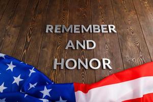 words remember and honor laid with silver metal letters on wooden background with USA flag underneath photo