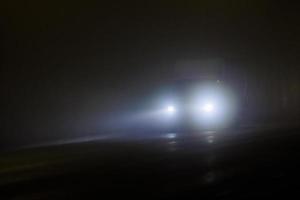 defocused alone minivan moving on empty night foggy road photo