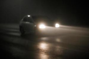 defocused photo of blurred car moving on empty night foggy road