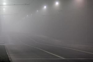 empty foggy night road with rows of lamp posts photo