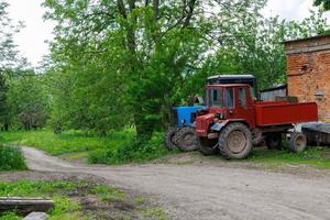 two old soviet tractors near brick building in summer day apple garden photo