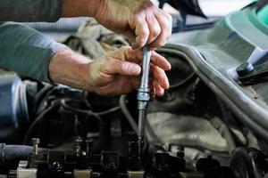 hands of caucasian mechanic unscrewing diesel engine parts of modern SUV photo