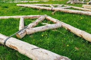 forged steel stripe connection of wooden log beams for roof support girder framework laid on green grass at summer day photo