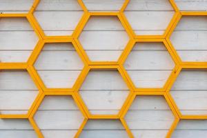 yellow honeycomb pattern wooden shelf on white painted wooden plank wall photo