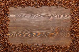 rectangular frame of many roasted coffee beans on brown wooden surface photo