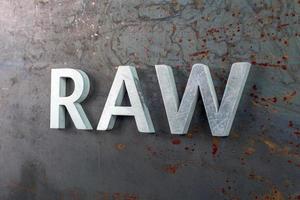 the word raw laid with silver metal letters on hot rolled steel sheet surface photo