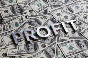 The word PROFIT laid with aluminium letters on the US dollar banknotes background - with selective focus photo