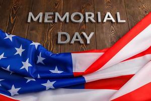 the words memorial day laid with silver metal letters on wooden board surface with crumpled usa flag photo