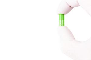 mano en guante médico sosteniendo ufo cápsula médica orgánica de color verde aislada sobre fondo blanco primer plano foto