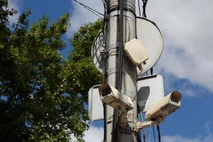 two old cctv security surveillance cameras on street light pole on blue sky background photo