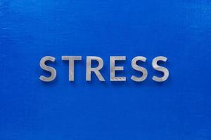 the word stress laid with silver metal characters on blue board in flat lay centered composition photo