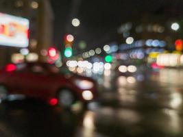 defocused night rain city street cross roads view with red car photo