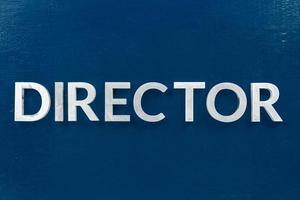 the word director laid with silver metal letters on classic blue painted board background photo