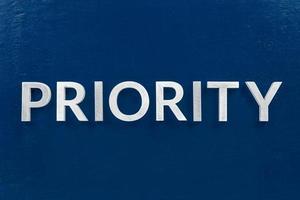 the word priority laid with silver letters on blue color surface photo