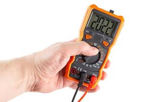 digit 2022 on lcd screen of digital electrical multimeter in left hand, isolated on white background photo