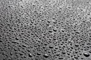 water drops on abstract flat black hydrophobic surface macro background with selective focus photo