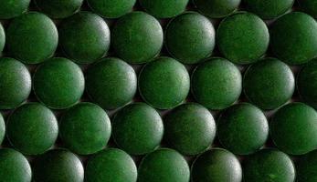 a seamless hexagonal pattern of many green organic spirulina tablets laid tight in one layer on flat surface photo