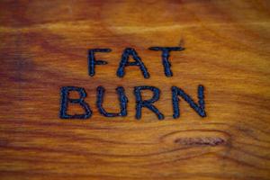 the words fat burn handritten on wooden surface with woodburner photo